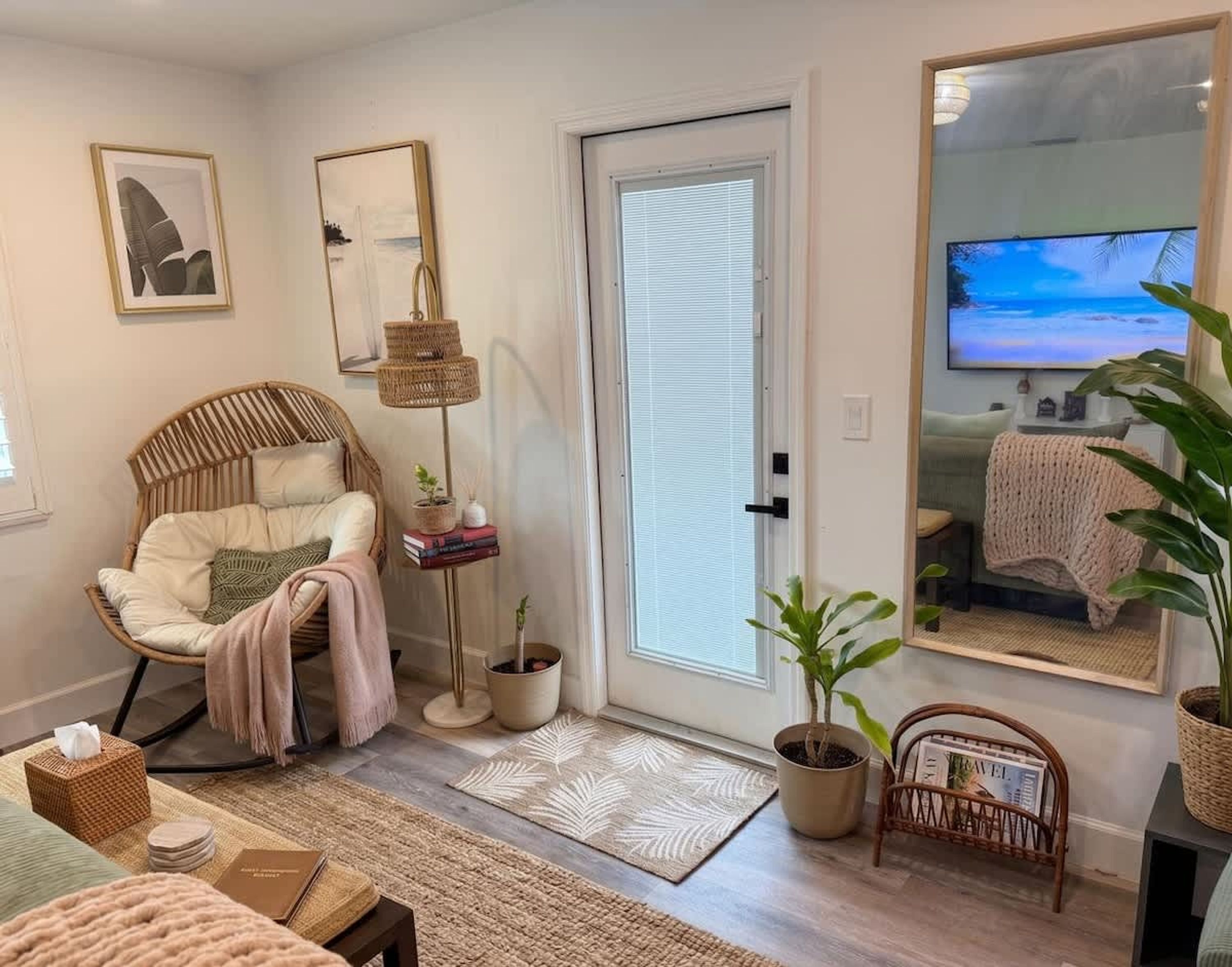 A cozy living room with a wicker chair, a floor lamp, a bookshelf, and a television.