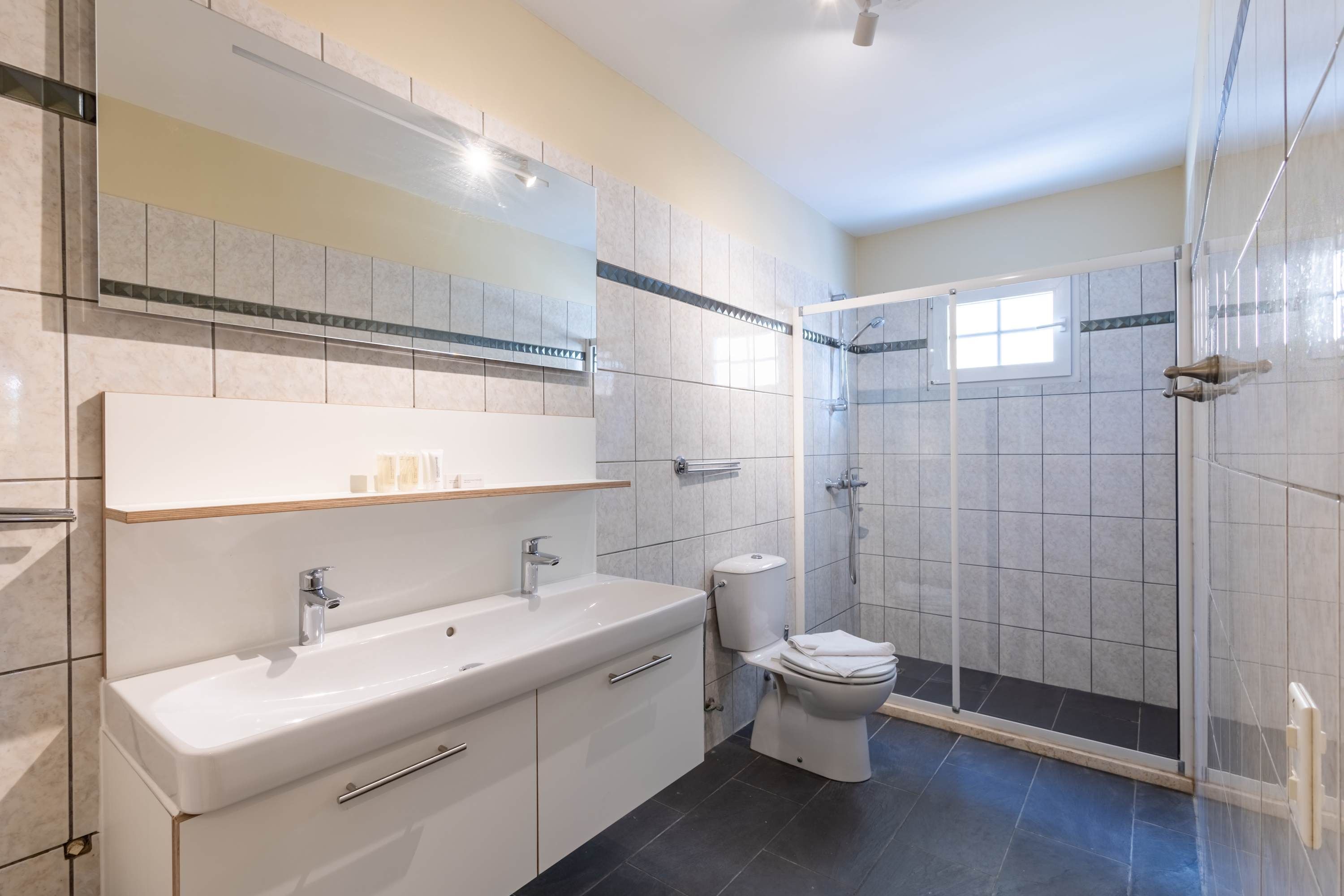 Un baño moderno con un espejo grande, un lavabo, un inodoro y una zona de ducha.