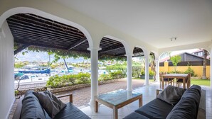 A covered outdoor seating area with a view of boats and greenery. - Spanish Water Marina Quad Residences (Jan Thiel)