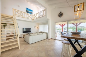 Ein modernes Wohnzimmer mit einem weißen Sofa, einem Fernseher und einer Holztreppe.