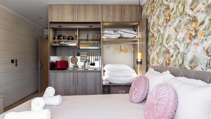 A hotel room with a bed, a wardrobe with hanging clothes, a kitchen area, and a bathroom. - Lemair Luxury Apartments Kozani Deluxe Double Room (Kozani)