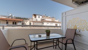 A balcony with a table and chairs, a potted plant, and a decorative wall. - Lemair Luxury Apartments Kozani Deluxe Double Room (Kozani)