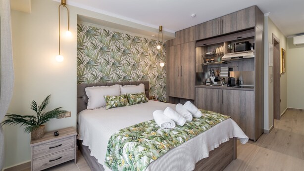 Un dormitorio con cama, mesita de noche y una zona de cocina integrada.