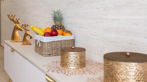 Un mueble blanco con una cesta tejida que contiene frutas y una decoración de reno dorado.