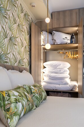 A bedroom with a bed, a closet with hanging clothes, and a shelf with pillows. - Lemair Luxury Apartments Kozani Deluxe Apartment (Kozani)