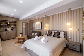 Ein modernes Hotelzimmer mit einem großen Bett, einer Sitzecke und einer Küchenzeile.