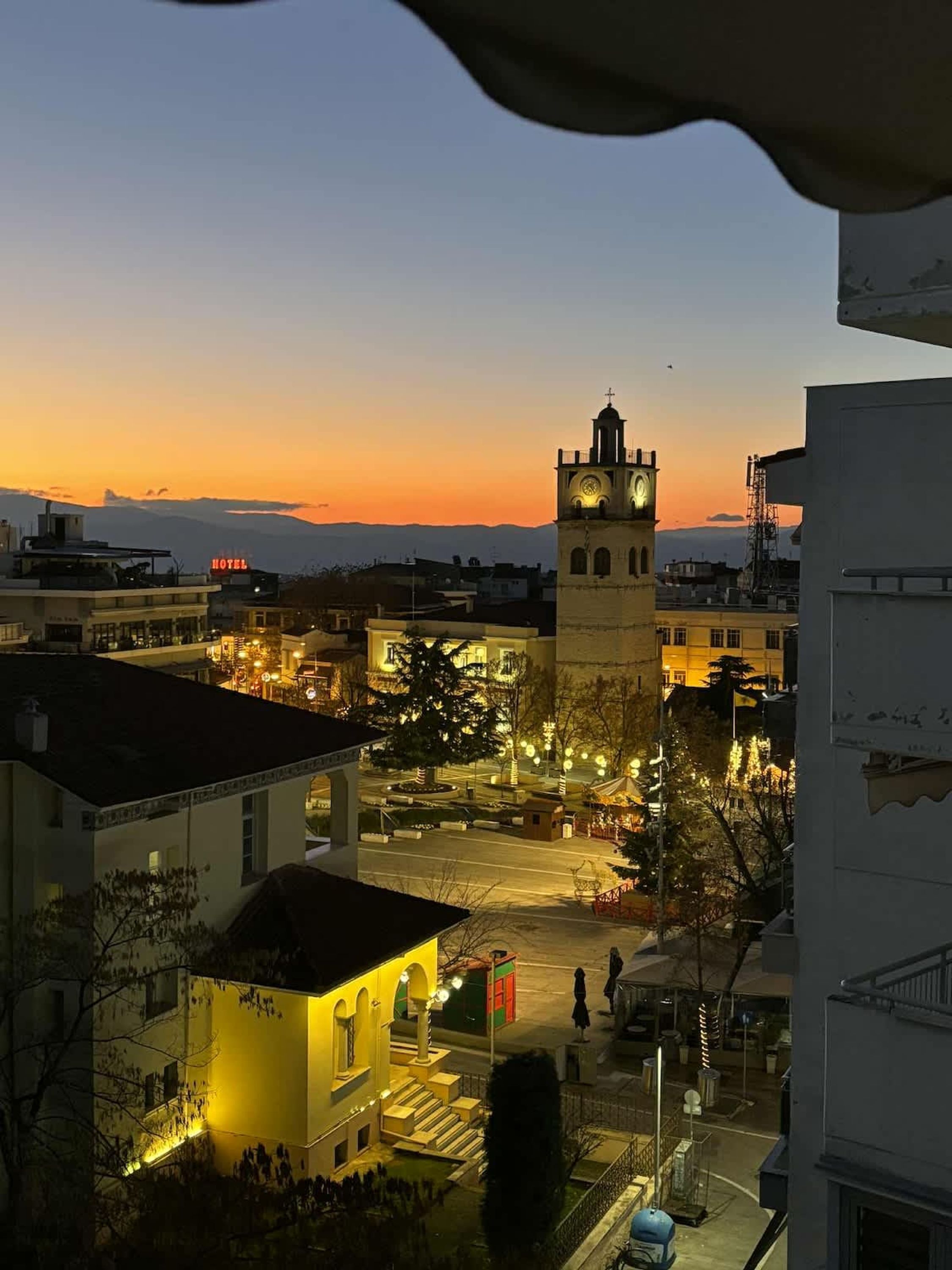 Un hotel con una torre de reloj, un patio interior y edificios circundantes.