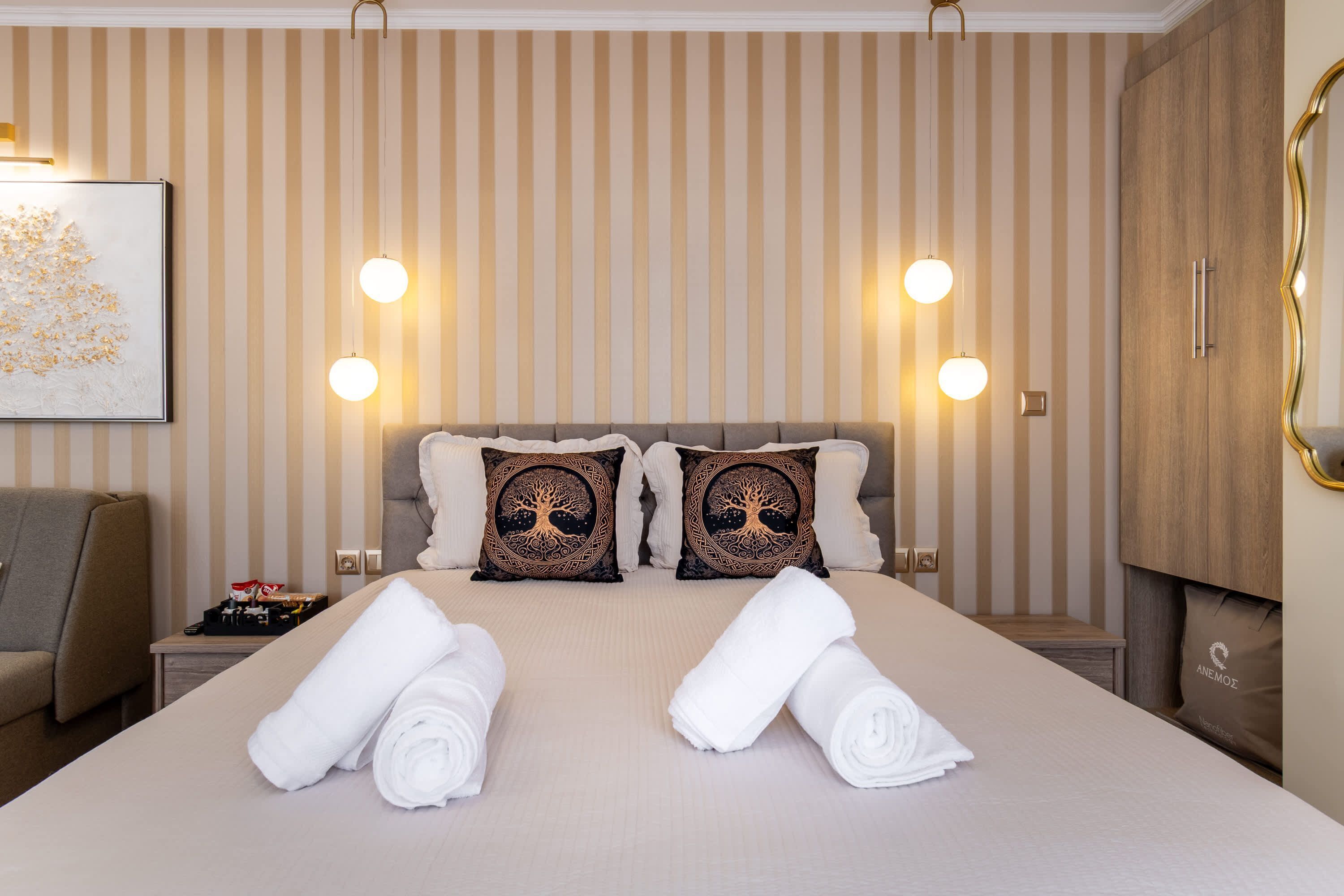 A hotel room with a large bed, two pillows with tree designs, bedside lamps, a nightstand, and a wardrobe.