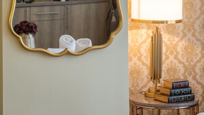 A modern kitchen with built-in appliances, a mirror with a gold frame, and a lamp on a side table. - Lemair Luxury Aprtmnts Kozani Deluxe Junior Suite (Kozani)