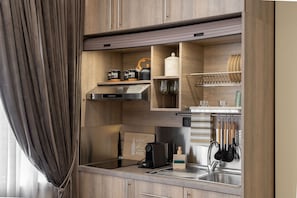 A compact kitchen with built-in appliances, wooden cabinetry, and a stainless steel sink. - Lemair Luxury Aprtmnts Kozani Deluxe Junior Suite (Kozani)