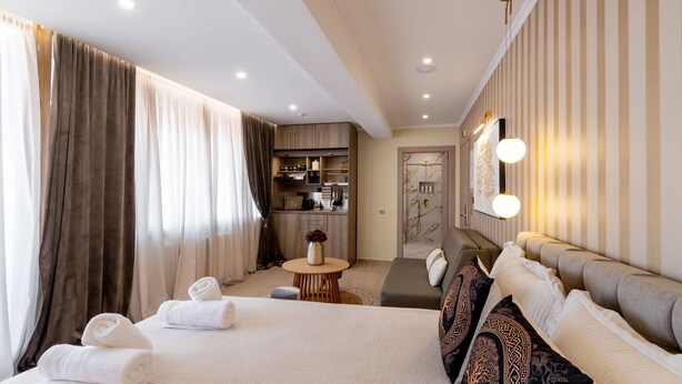 A hotel room with a bed, a sofa, a dining area, and a kitchen. - Lemair Luxury Aprtmnts Kozani Deluxe Junior Suite (Kozani)