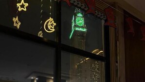 Uma área de refeições com uma mesa posta para dois, uma janela com vista para o horizonte urbano e iluminação decorativa.