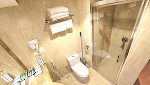 Casa de banho com sanita, cabine de duche com vidro, suporte para toalhas e secador de mãos.