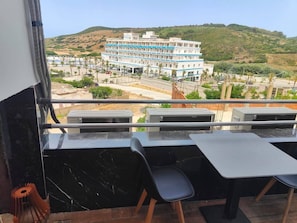 Une chambre d’hôtel avec un balcon, donnant sur un immeuble, et comprenant une table avec des chaises.