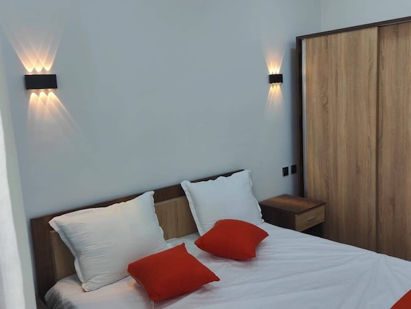 Une chambre moderne avec une tête de lit en bois, une table de chevet en bois et une armoire.