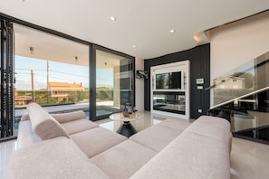 A modern living room with a glass door leading to a balcony, a round table with a vase and wine glasses, and a sofa. - Villa Weiss 2 (Vir)