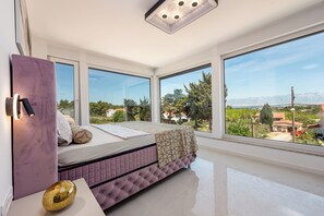 A bedroom with a bed, large windows, and a view of the landscape. - Villa Weiss 2 (Vir)