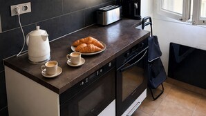 Eine moderne Küche mit weißen Schränken, einer dunklen Arbeitsplatte, einem Toaster, einem Wasserkocher und einer Platte Croissants.