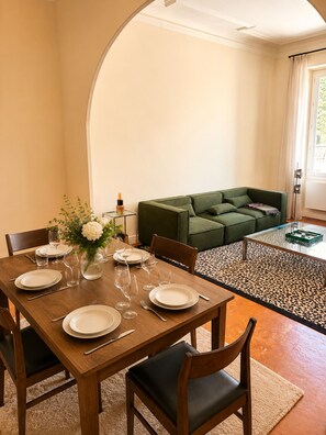 A dining area with a wooden table set for four, a green sofa, and a glass coffee table. - L'appartement Consolat (Marseille)