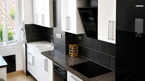 Eine moderne Küche mit weißen Schränken, einem schwarzen Kühlschrank und einem eingebauten Backofen.