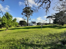 Un campo cubierto de césped con una casa blanca al fondo.