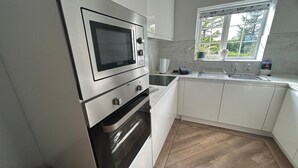 Ett modernt kök med vitvaror i rostfritt stål, en inbyggd ugn och ett fönster som släpper in naturligt ljus.