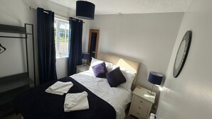 A bedroom with a bed, bedside tables, a mirror, and a window with curtains.