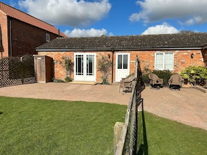 A brick house with a tiled roof, a front door, and a small porch with wicker chairs. - Private Fishing Lake Cottage - Pet Friendly w/ (Burgh le Marsh)