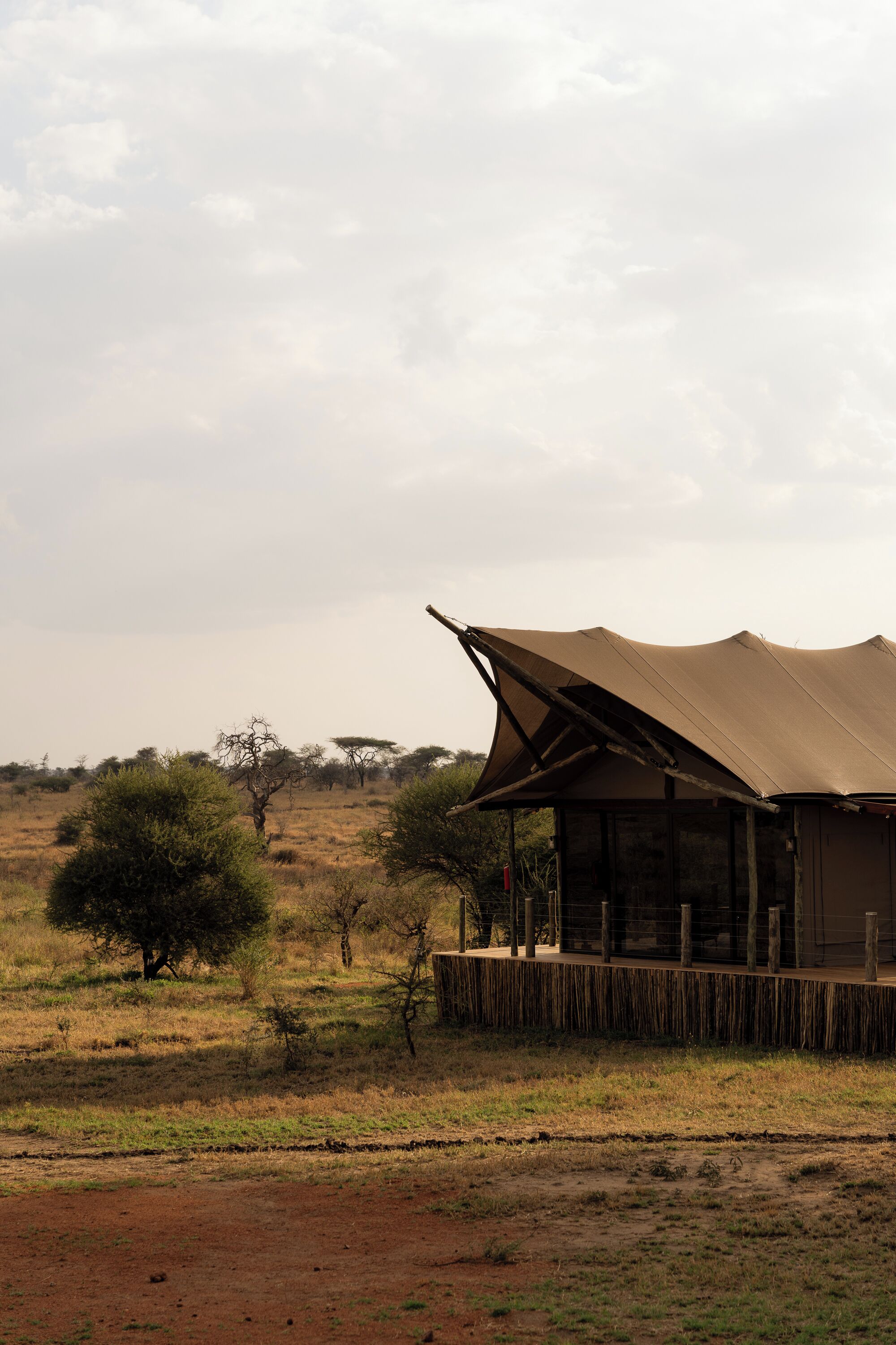 A building with a large overhanging roof, surrounded by a dry landscape with sparse trees.