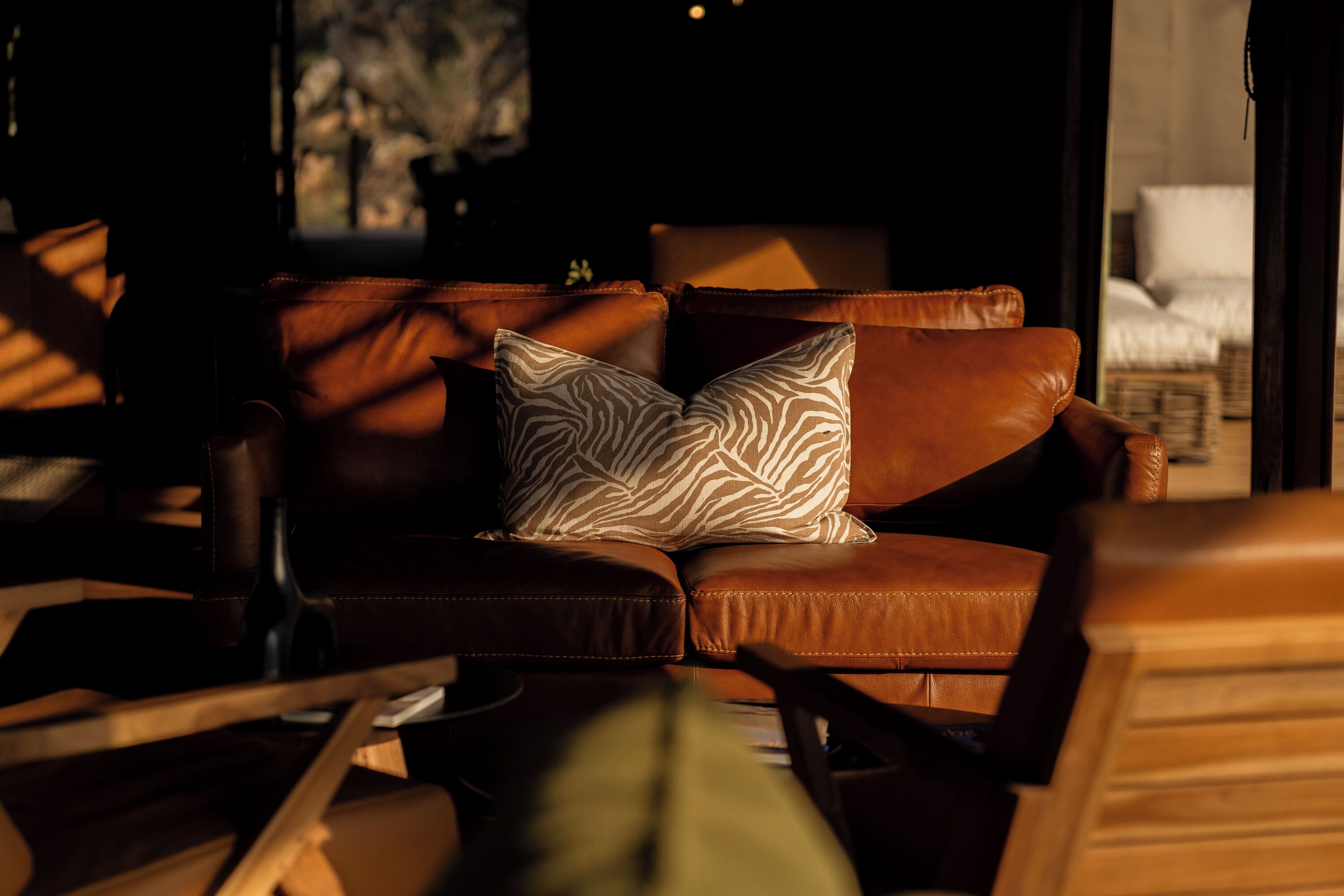 A leather sofa with a zebra-patterned pillow in a dimly lit room.