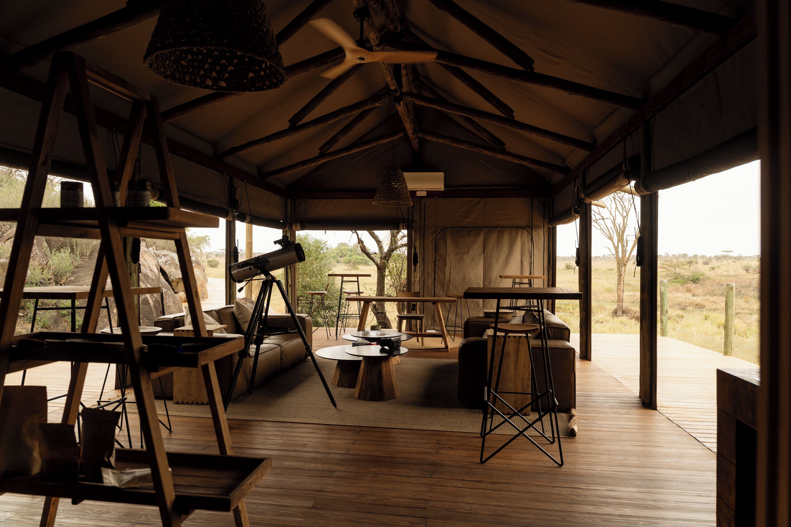 A tented accommodation with a wooden deck, seating areas, and a view of the outdoors.