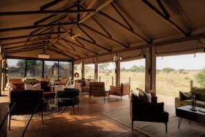 A spacious interior with a high ceiling, wooden beams, and large windows offering a view of the outdoors. - Kuona Serengeti (Serengeti)