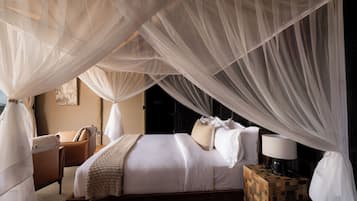 Ein Schlafzimmer mit Baldachinbett, Nachttischen und einem Sessel.