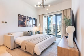 Ein modernes Hotelzimmer mit einem großen Bett, einem Balkon mit Blick auf die Stadt und einem Flachbildfernseher.