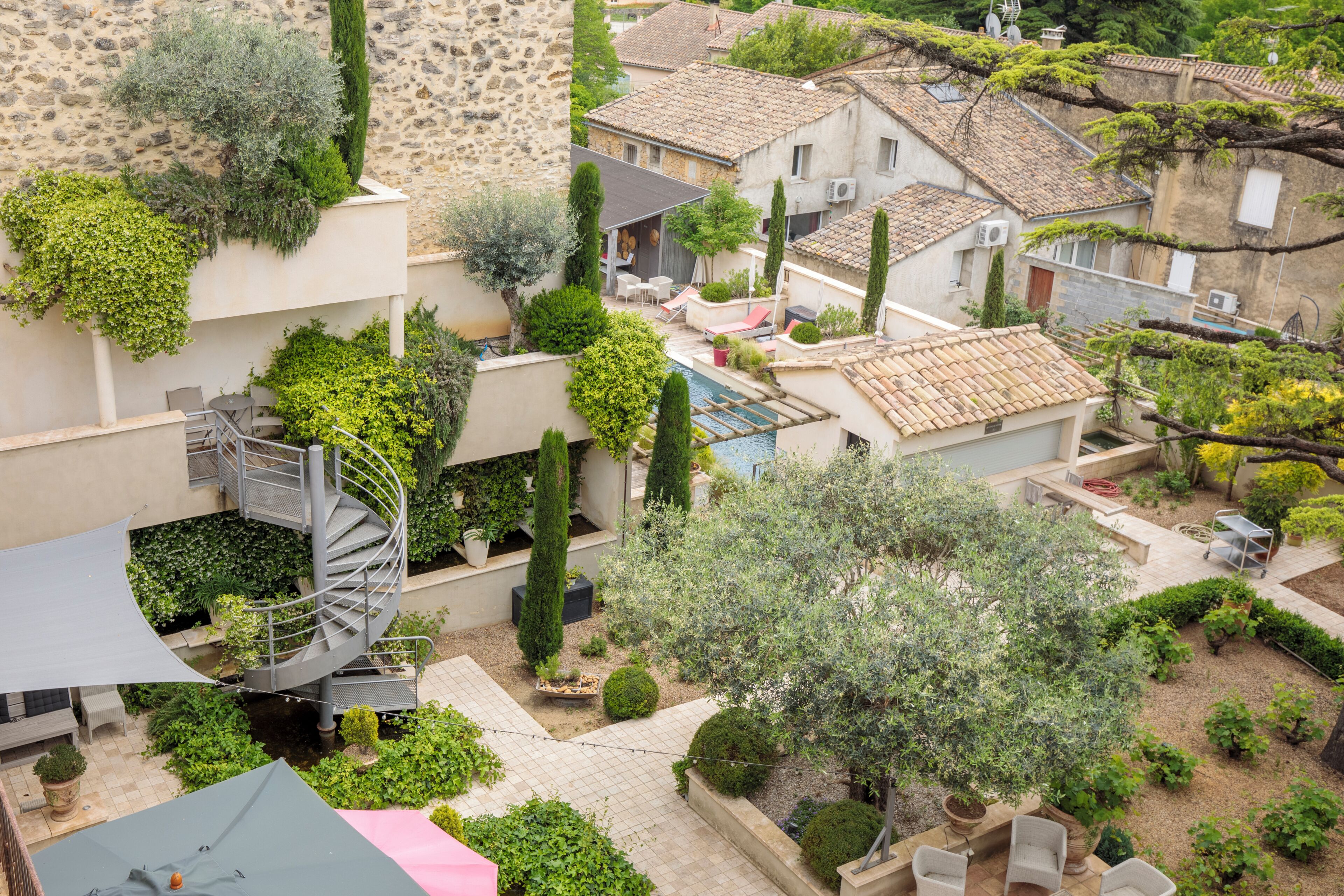A residential area with stone buildings, a spiral staircase, and a small garden with potted plants.