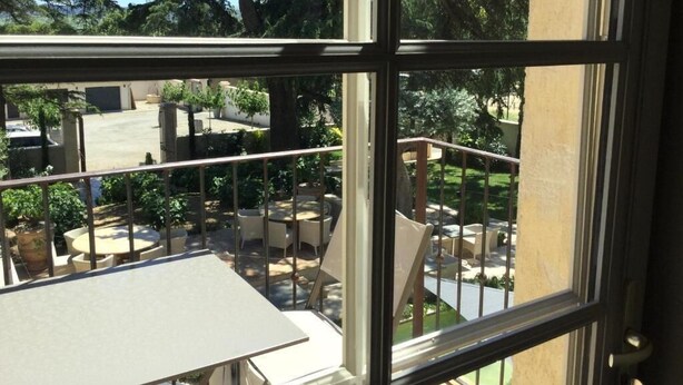 A balcony with a view of outdoor seating and trees. - Boutique Hôtel La Villa Montesquieu (Laudun)