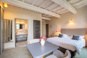 Una habitación de hotel con cama, mesita de noche y baño con lavabo y espejo.