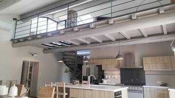 Una cocina moderna con una isla central, armarios de madera y una escalera que sube a un nivel superior.