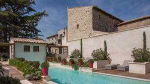 A pool area with a stone building, potted plants, and outdoor seating. - Boutique Hôtel La Villa Montesquieu (Laudun)