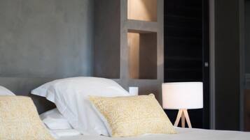A hotel room with a bed, pillows, a bedside lamp, and a view through a window.