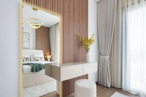 Ein modernes Schlafzimmer mit großem Spiegel, Nachttisch, Bett, Ablagetisch und Fenster mit Vorhängen.