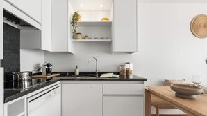 Una cocina moderna con armarios blancos, una encimera negra y un lavaplatos integrado.