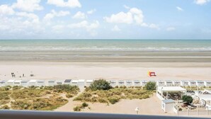 Vista de la playa con una hilera de cabañas, una torre de salvavidas y un edificio con terraza.