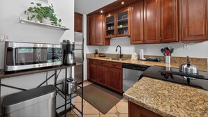 Eine moderne Küche mit Granit-Arbeitsplatten, Edelstahlgeräten, Holzschränken und einem eingebauten Backofen.