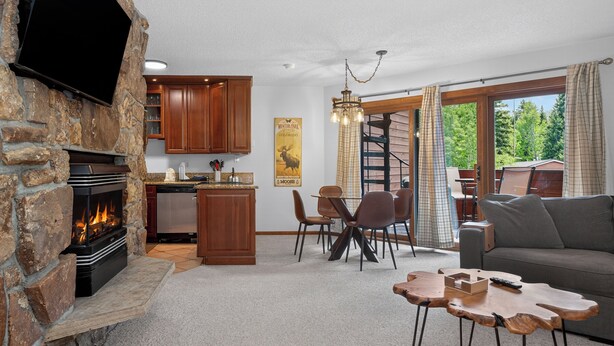 Ein Wohnzimmer mit Kamin aus Stein, Holzsäulen und einer Essecke, sowie einem Sofa.