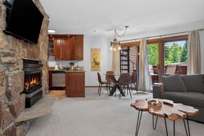 Una sala de estar con chimenea de piedra, armarios de madera, un comedor y un sofá.