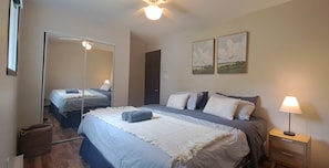 A bedroom with a bed, a bedside lamp, a mirror, and two paintings on the wall. - Waterfront Getaway with a Spa • Family-friendly chalet that sleeps 11 (Lac-des-Plages)