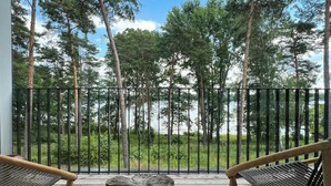 Een houten terras met twee stoelen en een houten tafel in het midden, met uitzicht op een bebost gebied.