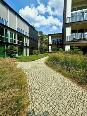 A pathway leading to modern buildings with large windows and balconies.