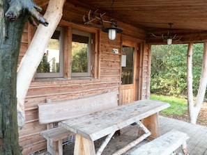Eine rustikale Holzhütte mit überdachter Veranda, einer Bank und einem hängenden Laternen.